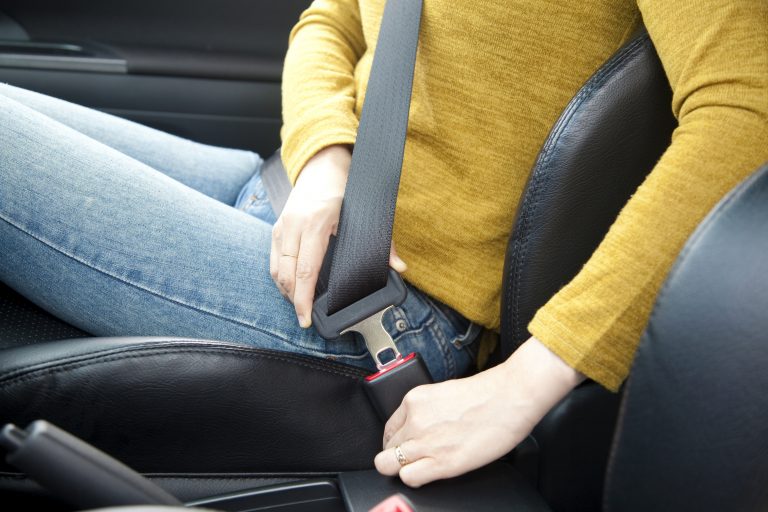 Person in einem Autositz, die sich gerade anschnallt.
